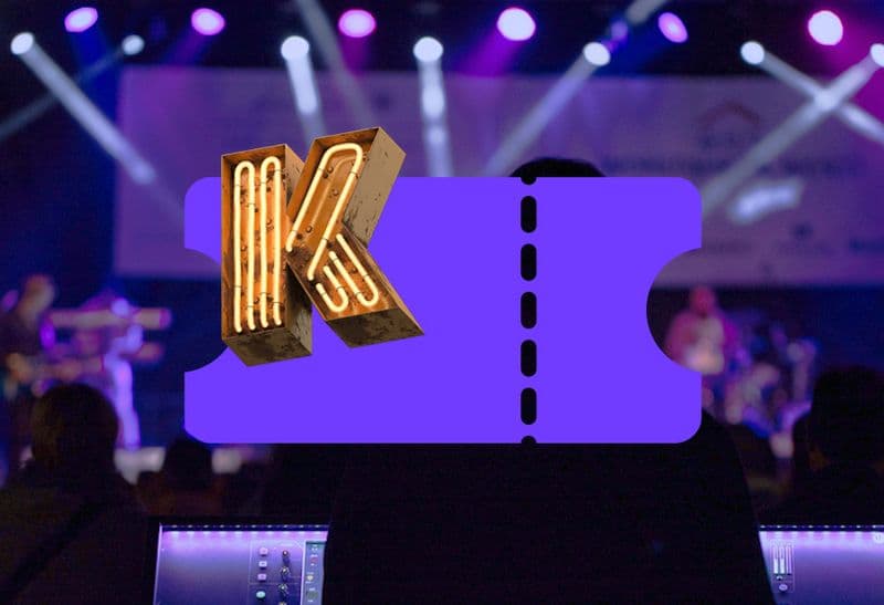 Leuchtendes K auf einem violetten Ticket vor einer Konzertbühne